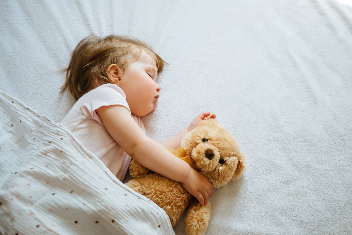 Cute Baby Sleeping on the Bed with a Stuffed Bear